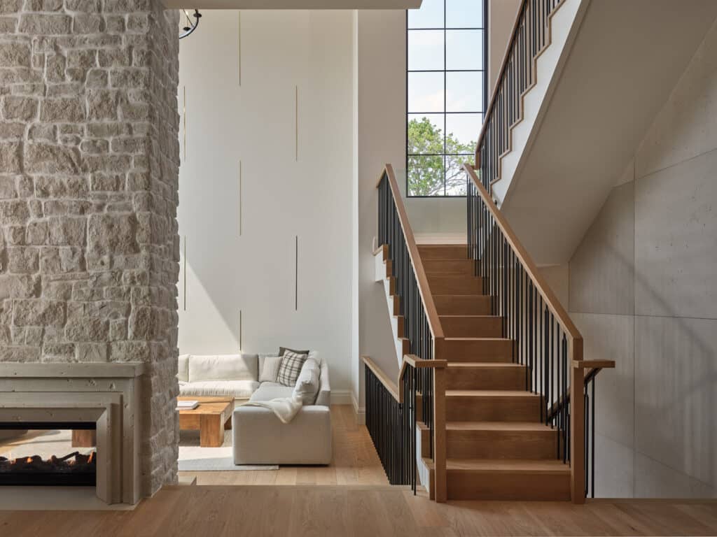 Sideroad living space with stone fireplace and staircase